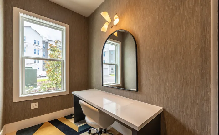 Chic home office area with natural light, featuring a modern desk and stylish accent mirror.