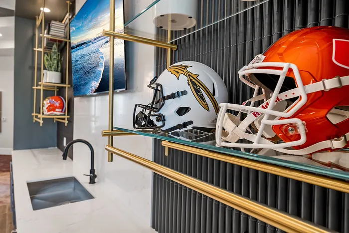 Chic apartment interior featuring a modern wet bar with display shelving, decorative plant, sports helmets, and dynamic wall art.