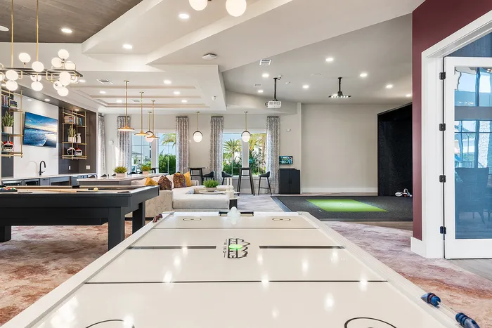 Luxurious apartment entertainment area featuring air hockey and pool tables with elegant lighting and a chic seating area.