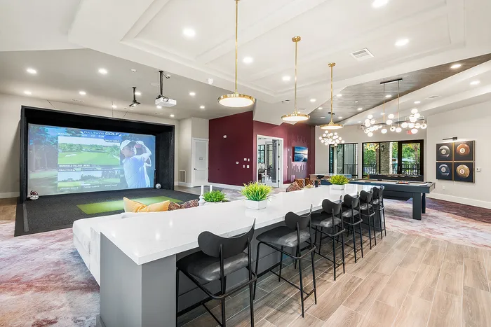 Luxurious entertainment room with golf simulator, modern bar seating, and chic lighting, perfect for social gatherings.