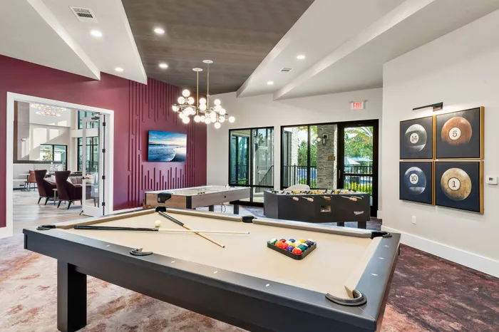 Elegant recreation room with a chic pool table, vibrant accent wall, and stylish lighting, offering a luxurious spot for relaxation and entertainment.