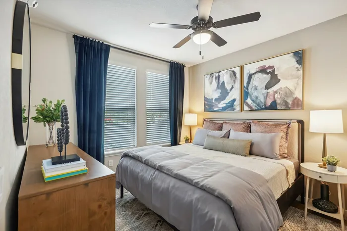 Cozy bedroom with modern artwork, plush bedding, and elegant furnishings bathed in natural light.