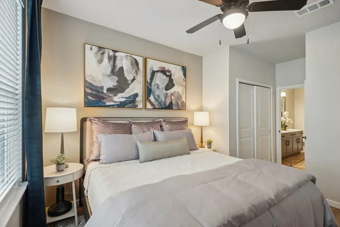 Inviting bedroom with modern decor, featuring a cozy bed, elegant lighting, and artistic wall art, creating a serene atmosphere.