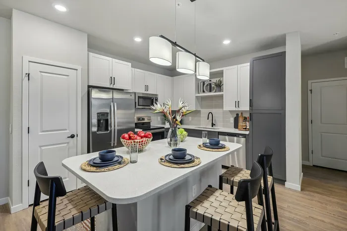 Modern kitchen featuring sleek white cabinetry, elegant pendant lighting, and a stylish island with seating.