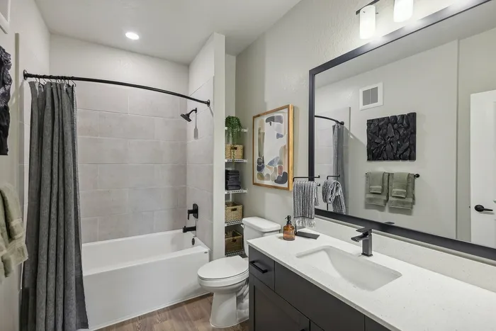 Elegant bathroom showcasing a modern vanity with ample counter space, sleek fixtures, and a serene shower area with tasteful decor.