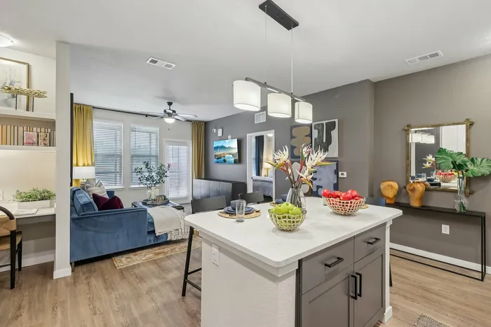 Chic open-plan apartment showcasing a modern kitchen island, cozy living area, stylish decor, and abundant natural light.