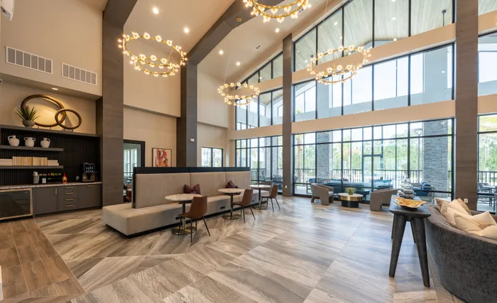 Elegant and spacious apartment lobby with high ceilings, modern chandeliers, and expansive windows offering abundant natural light.