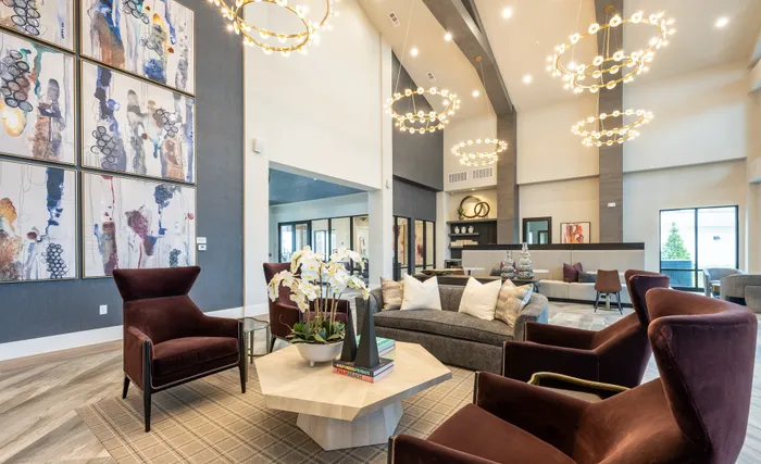 Luxurious lounge showcasing high ceilings, modern chandeliers, and chic seating with elegant art decor.