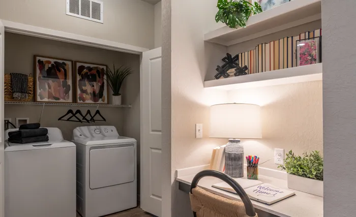 Charming laundry nook featuring washer and dryer, stylish art, and a cozy workspace with ambient lighting.