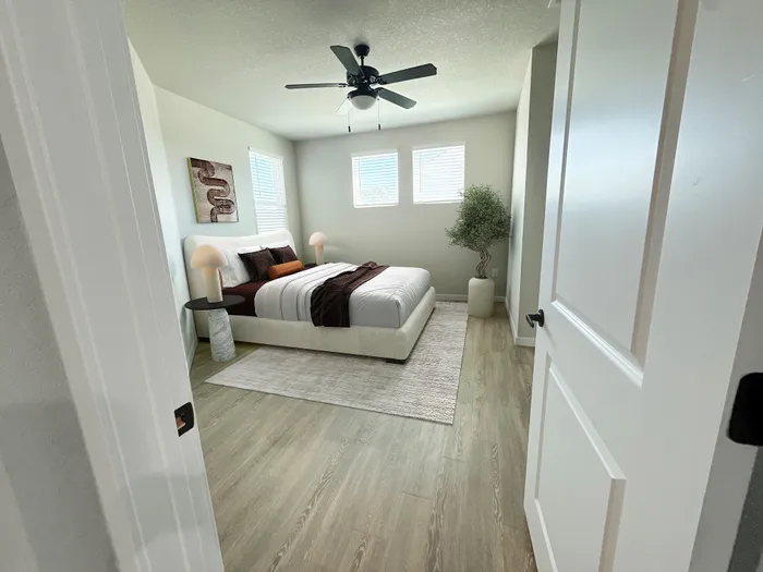 Inviting bedroom with elegant decor, featuring a plush bed, stylish bedside lamps, vibrant art piece, and abundant natural light from three windows.
