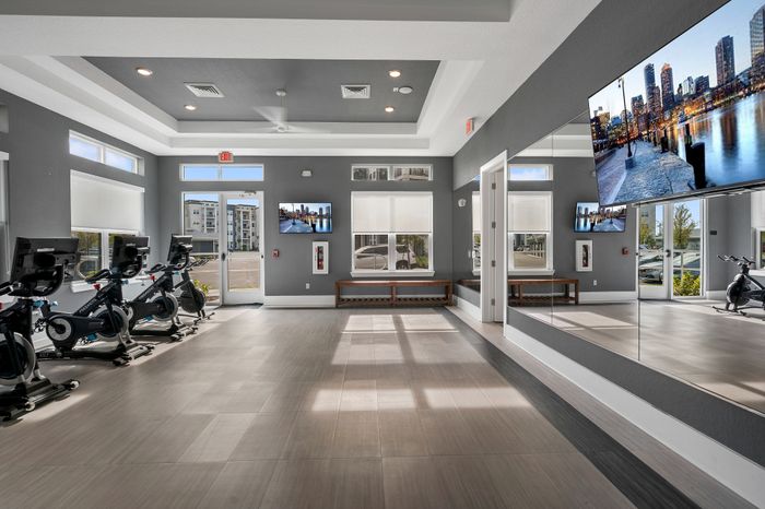 Modern apartment fitness center featuring sleek exercise bikes, mirrored walls, and ambient lighting for an inspiring workout experience.