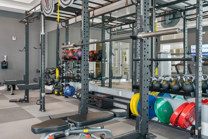 Modern fitness center with various gym equipment including weights, kettlebells, and a bench press, perfect for a comprehensive workout.