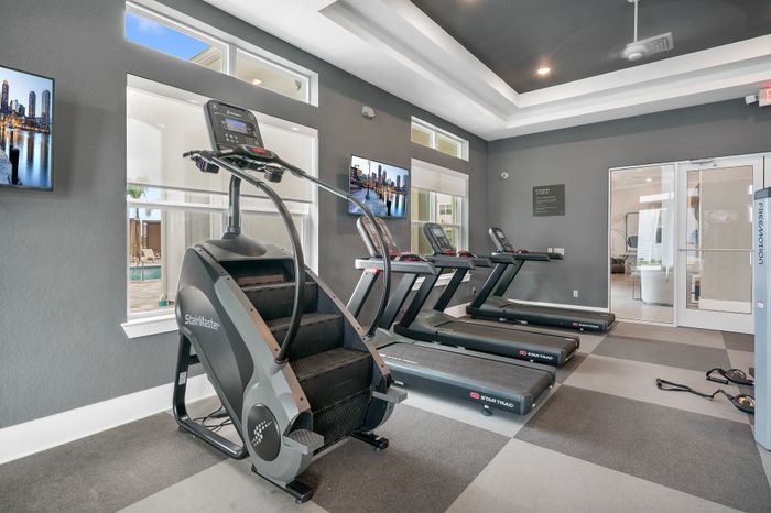 Modern fitness center with state-of-the-art StairMaster and treadmills, offering a bright and inviting workout space.