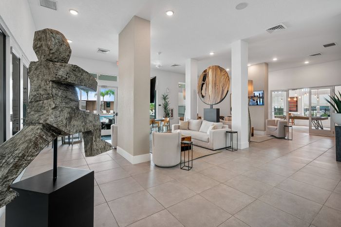 Luxurious apartment lobby featuring modern sculpture, plush seating, and elegant decor under soft lighting.