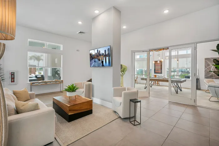 Contemporary lounge with plush seating, a stylish wooden coffee table, and a wall-mounted TV, offering a bright and inviting atmosphere.