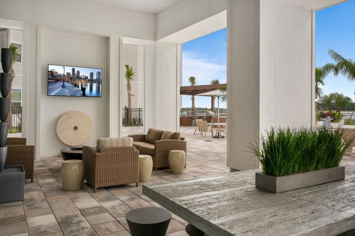Luxurious open-air lounge with wicker seating, stylish decor, and a sunny patio view.