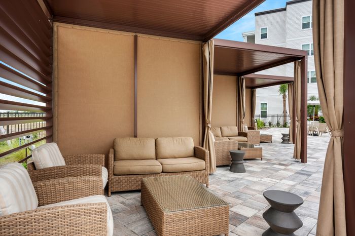 Luxurious outdoor seating area featuring stylish wicker furniture and elegant drapery, perfect for relaxing and entertaining.
