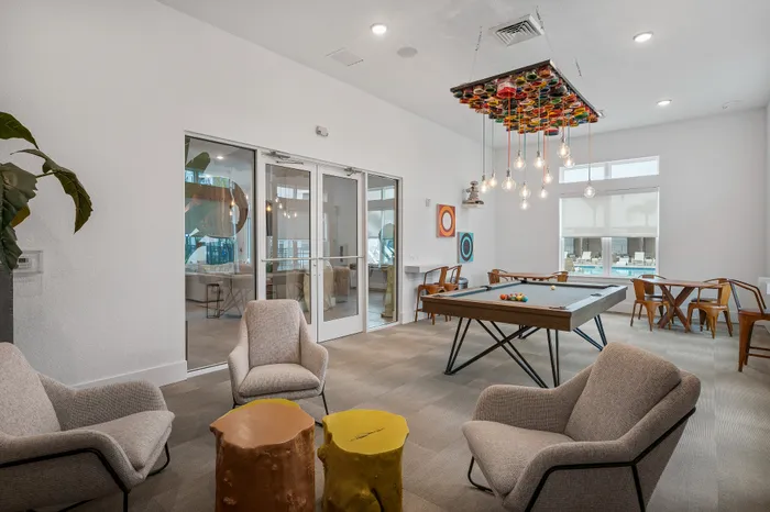 Contemporary recreation room with chic seating, a stylish pool table, and artistic lighting, ideal for relaxation and socializing.