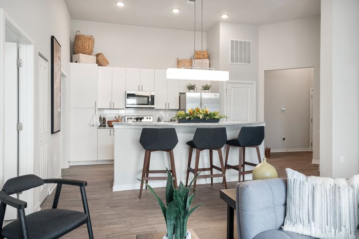 Modern kitchen with sleek white cabinetry, stainless steel appliances, and a stylish breakfast bar with elegant seating.