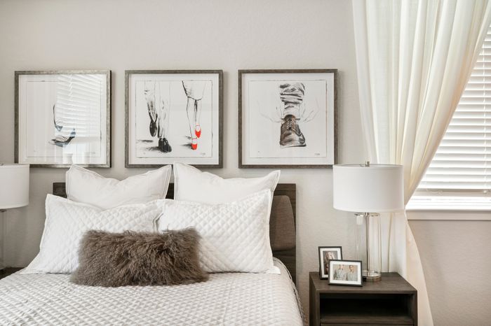 Chic bedroom with elegant wall art and soft plush bedding, enhanced by natural light filtering through stylish blinds and curtains.