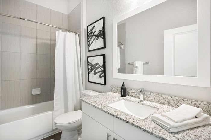 Elegant bathroom with sleek granite countertops, modern fixtures, and chic abstract wall art.
