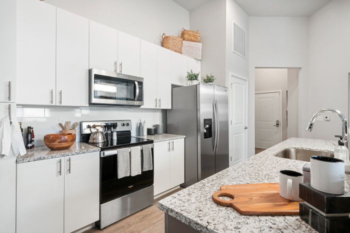 Modern kitchen with sleek stainless steel appliances, elegant white cabinetry, and stylish granite countertops.
