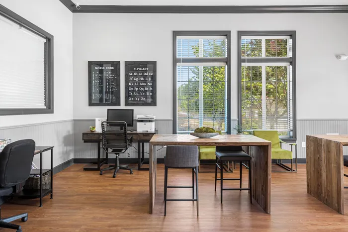 Bright and inviting office space featuring stylish wooden desks, modern decor, and large windows showcasing lush greenery.