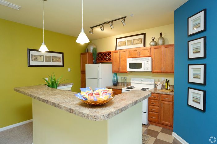 Modern kitchen with bright accents, featuring a stylish breakfast bar, elegant pendant lighting, and polished wooden cabinetry.