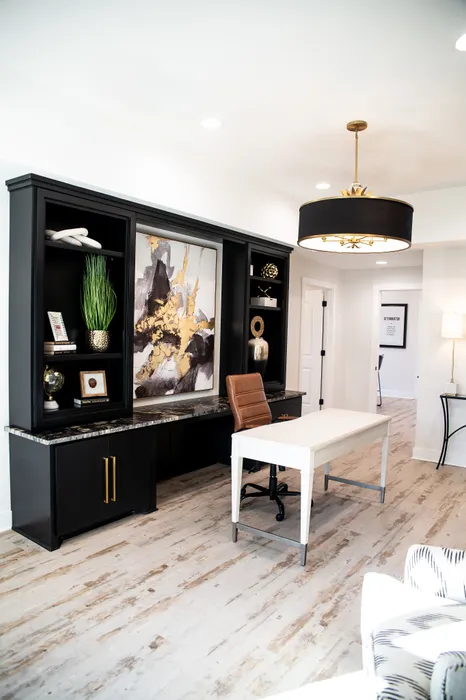Elegant home office with chic black cabinetry, stylish artwork, and a modern chandelier.