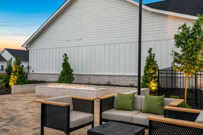 Charming patio area with cozy seating, stylish lighting, and inviting outdoor fireplace for ideal evening gatherings.