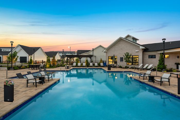 Charming residential pool area at dusk with elegant seating, lush landscaping, and inviting ambiance for relaxation.