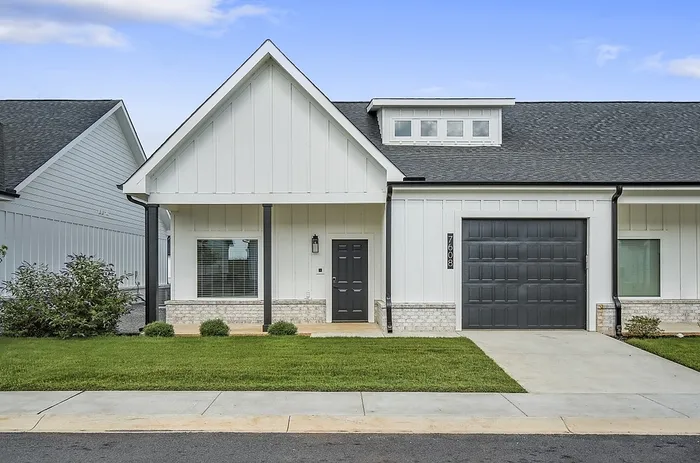 Charming modern home with a white exterior, sleek black accents, and a well-manicured lawn, showcasing elegant simplicity.