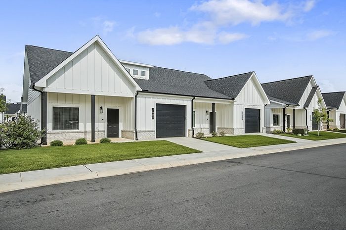 Charming row of modern townhouses with white exteriors and inviting front lawns, perfect for family living.