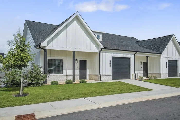 Charming modern townhouse exterior with sleek white siding, inviting front porch, and manicured green lawn.