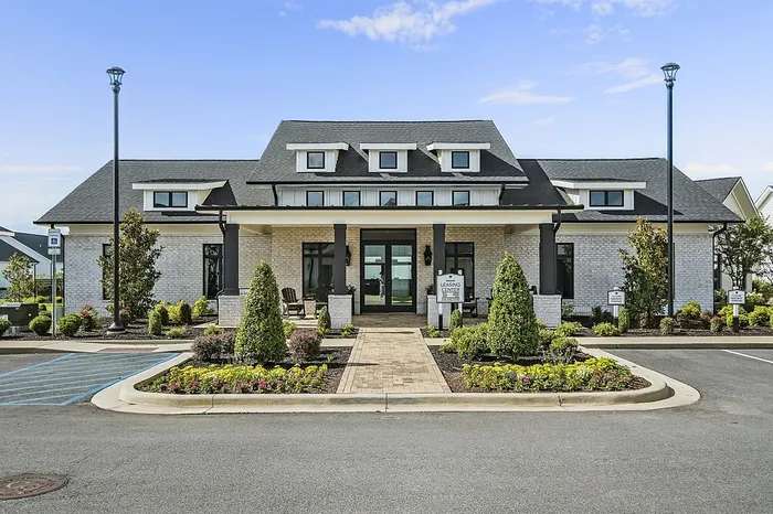 Elegant apartment leasing center with a welcoming entrance and manicured landscaping under a clear blue sky.