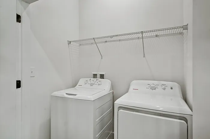 Modern laundry room with sleek washer and dryer, featuring a convenient overhead wire shelf for storage.