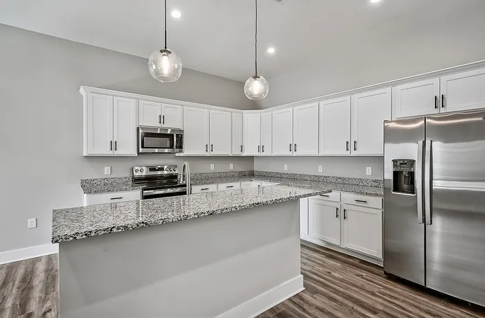Modern kitchen with sleek granite countertops, stainless steel appliances, and elegant pendant lighting.
