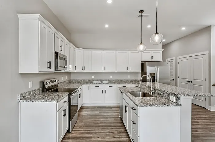Modern kitchen with sleek granite countertops, elegant white cabinetry, and stylish pendant lighting.