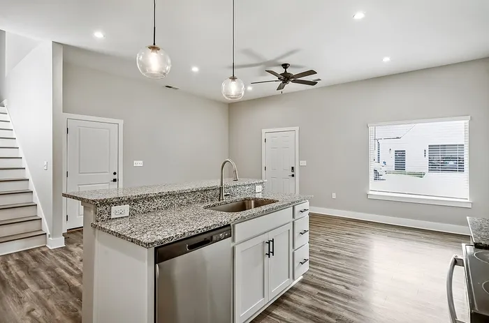 Contemporary open kitchen with sleek granite countertops, modern stainless steel appliances, and elegant pendant lighting in a bright, inviting space.