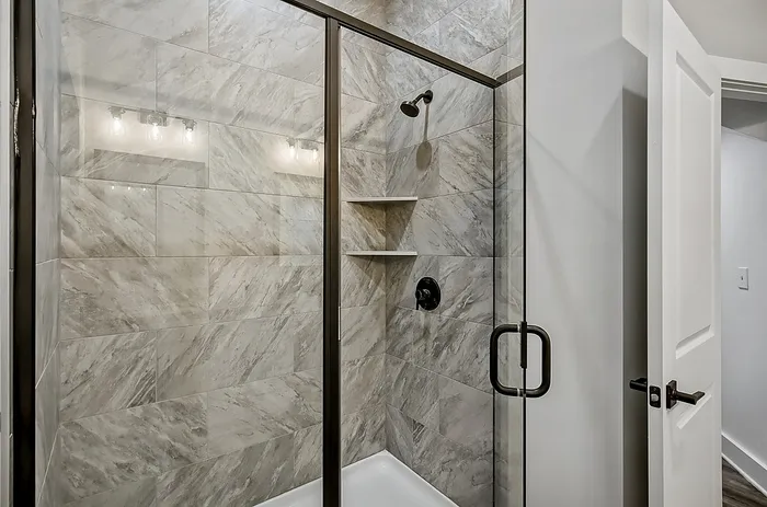 Elegant modern shower with sleek glass doors and chic marble tiles.