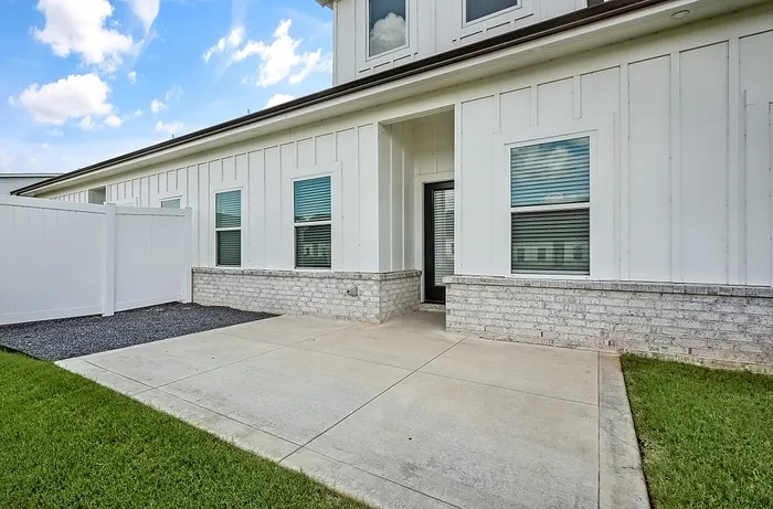 Charming exterior view of a modern home with white siding, stylish windows, and a cozy front garden area.