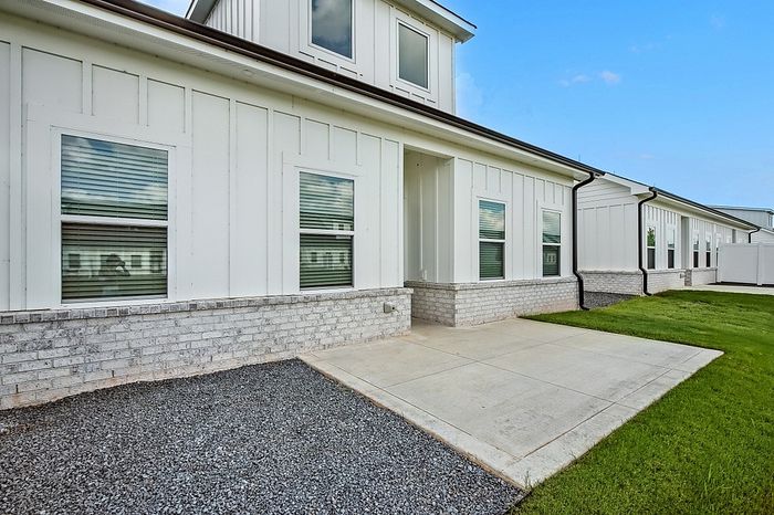 Charming modern exterior with sleek white paneling and inviting pathway surrounded by lush green lawn.