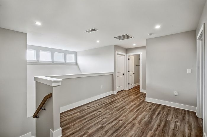 Bright and open hallway with modern wood flooring and stylish recessed lighting, perfect for creating a welcoming entryway.