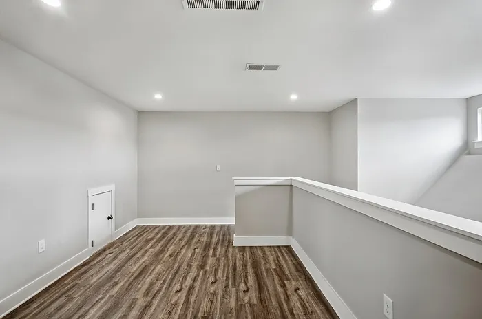 Bright and modern loft space with sleek wooden flooring and recessed lighting, ideal for a cozy living area or creative workspace.
