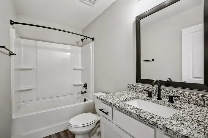 Elegant bathroom featuring a granite countertop, sleek black fixtures, and a modern bathtub.