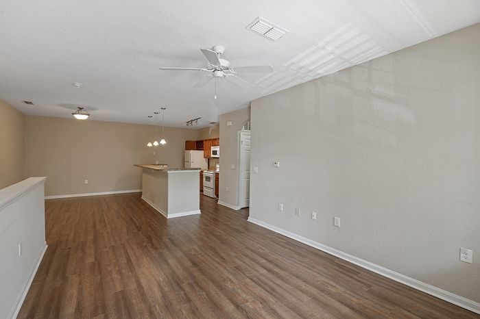 Inviting open-plan apartment with elegant wooden flooring, modern kitchen island, and bright natural lighting.