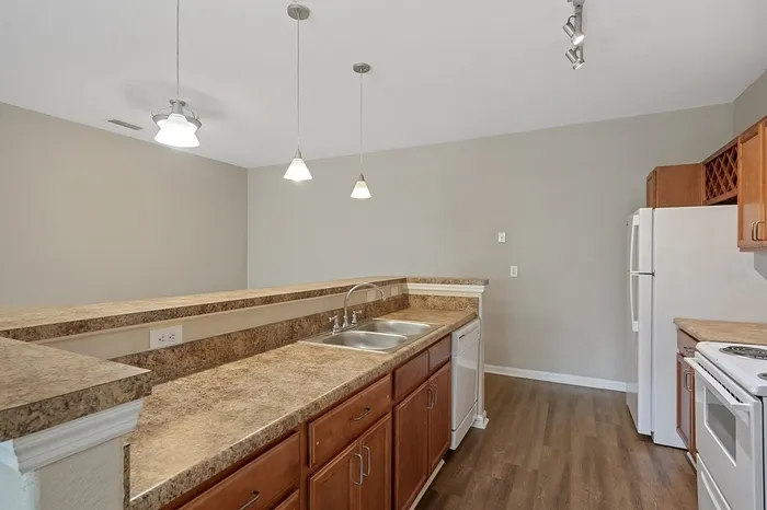 Inviting modern kitchen with sleek countertops, warm wooden cabinetry, and stylish pendant lighting.