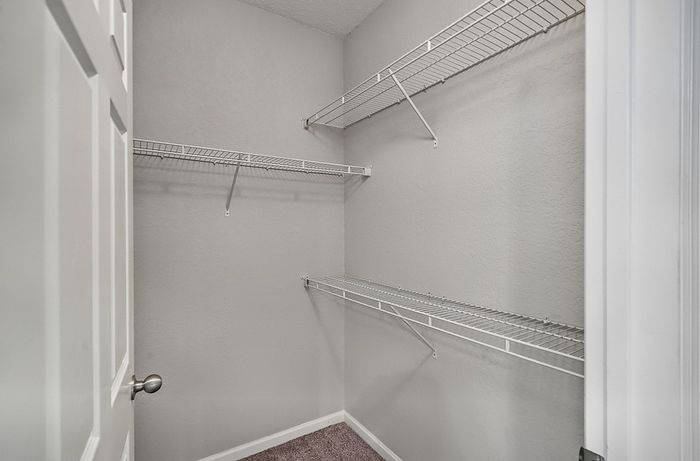 Spacious walk-in closet with sleek wire shelving, perfect for organized storage and maximizing space.