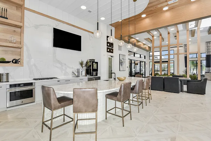 Modern open-concept community space featuring a sleek marble countertop, stylish bar stools, and a comfortable seating area with abundant natural light.