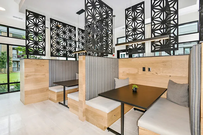 Modern dining area with stylish wooden booth seating and decorative geometric panels, offering a sleek and inviting atmosphere.
